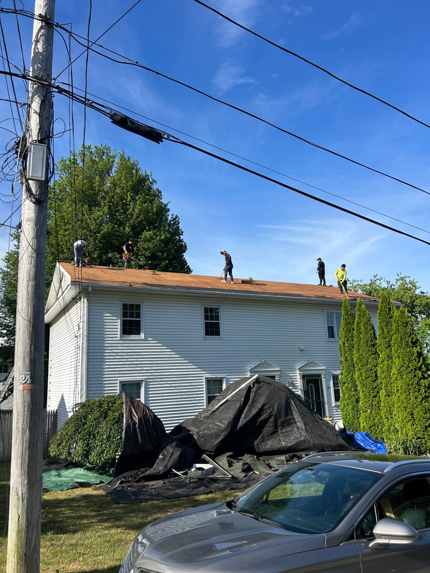 Roofing crew inspecting and removing storm-damaged shingles on a Rhode Island property